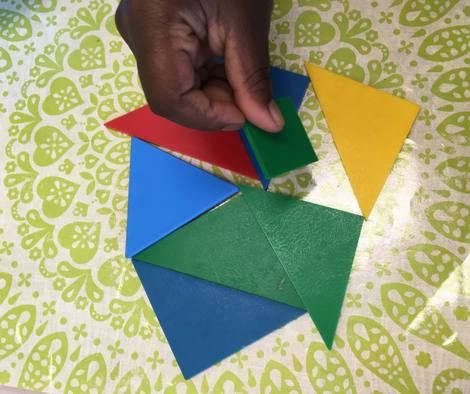 student hand placing tangram blocks on a work mat