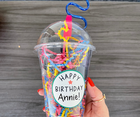 a plastic cup filled with colorful confetti, a crazy straw, and a sticker on front that reads, "Happy Birthday, Annie!"