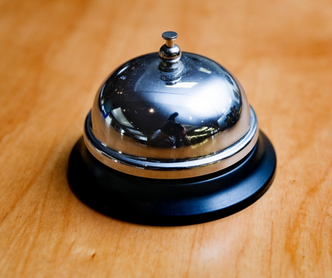 A hotel-front desk-style bell on a wooden surface